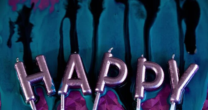 Birthday candles. Happy holiday. Ink drip. Festive font. Metallic shiny wax letter in iridescent glow light with blue black color paint spill on pink surface abstract art background.