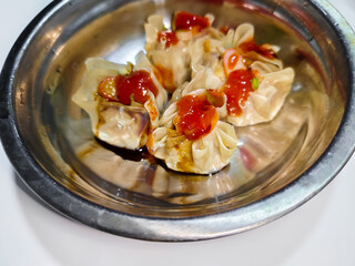 a bowl of dim sum sprinkled with dark soy sauce and sauce on a white background