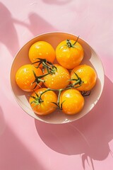 Yellow tomatos in plate on pink background. Aesthetic summer vibe vegetables wallpaper.