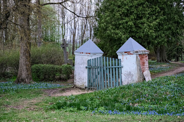 old crooked cemetery gate with white columns. Jačūnu kapi, Latvia, Zemgale