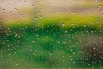 Drops of water on a wet glass with natural green background. Rain drops pattern on smooth surface....