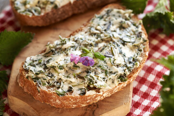 Nettle butter - homemade bread spread made of wild edible plants harvested in spring on a slice of...