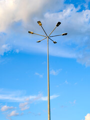 A pillar of street lighting with several lanterns against a gray sky. The concept of urban infrastructures in electric lighting. Electrical fittings with a system for increasing light in the dark.