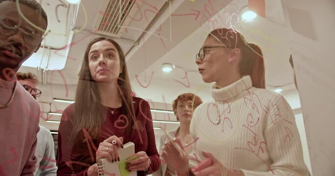 A multiracial group of employees participates in a brainstorming session, using sticky notes on a glass wall in a bright, contemporary workspace, fostering creativity and collaboration.
