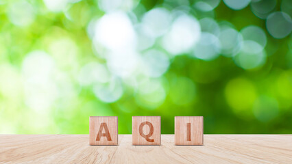 AQI, Abbreviation of air quality index word written on wooden blocks. text AQI on nature background, environment concept.