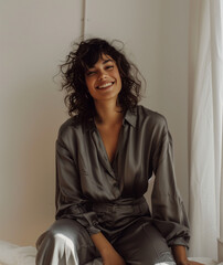 model, beautiful woman in silk gray pajamas sitting while posing