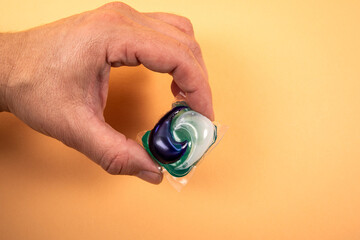 Laundry capsule in hand on light background