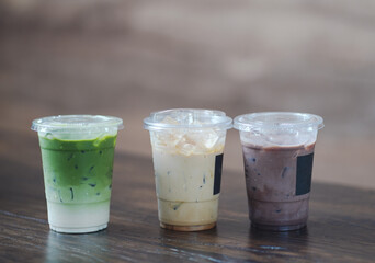 Close up glass of ice matcha green tea, iced latte and ice chocolate on wooden table of a coffee shop summer terrace, menu photography.