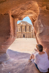 Petra, Jordan; April 08, 2024 - A woman enjoys a view of the Monastery in Petra, Jordan from a cave.