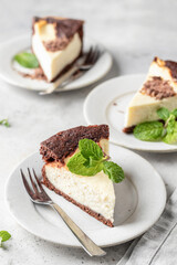 Piece of homemade chocolate cheesecake with mint leave on a plate on white textured background