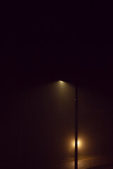 Single streetlamp glowing in the dark with fog air