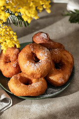 Delicious homemade crumpets or fried donuts sprinkled with powdered sugar on gray tile kitchen background in hard light