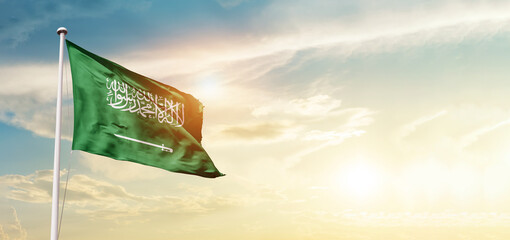 Saudi Arabia flag in waving in beautiful sky with sunlight. - obrazy, fototapety, plakaty