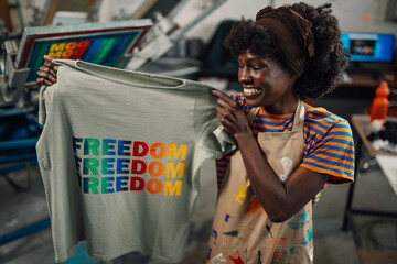 Multiracial press woman holding silkscreen printed t-shirt and smiling