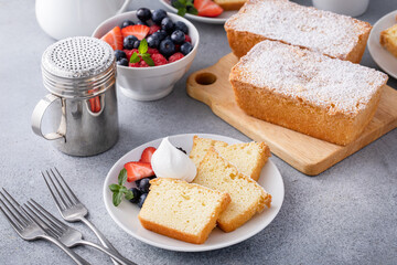 Traditional vanilla pound cake sliced and served with whipped cream and berries