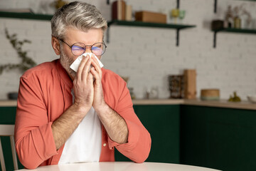 Unhealthy man sneezing with handkerchief suffering from cold flu