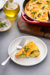 Healthy frittata or quiche with broccoli and red pepper cooked in a cast iron pan, slice on a plate
