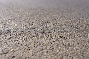 Fototapeta na wymiar A close up of a grey concrete surface with many small rocks scattered across it