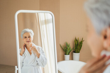 Love yourself. Beautiful old woman enjoying mirror reflection. Senior older lady spending morning in bathroom looking at mirror confident happy. Woman doing daily morning beauty routine. Self love
