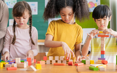 Portrait of asian caucasian little children playing blocks in classroom. Learning by playing education group study concept. International pupils doing activities brain training in primary school.