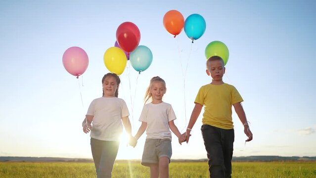 children in balloons in the park. children walk in nature in park with balloons. happy family kid holiday concept. children view from dream back silhouette walk in nature at sunset holding balloons