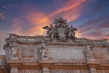 Historical facade featuring ornate sculptures, crest with papal tiara and keys, Latin inscriptions...
