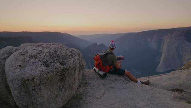 Incredible panoramic view of mountain range in Yosemite national park after sunset, male backpacker looking in the distance, enjoying silence and seclusion. High quality 4k footage