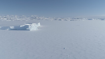 Frozen iceberg in Antarctica ocean ice desert water up to horizon. Antarctic polar winter. Aerial view of iceberg locked in ice Antarctica landscape. Polar Frozen ocean covered with snow. South nature