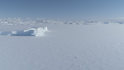 Frozen iceberg in Antarctica ocean ice desert water up to horizon. Antarctic polar winter. Aerial...