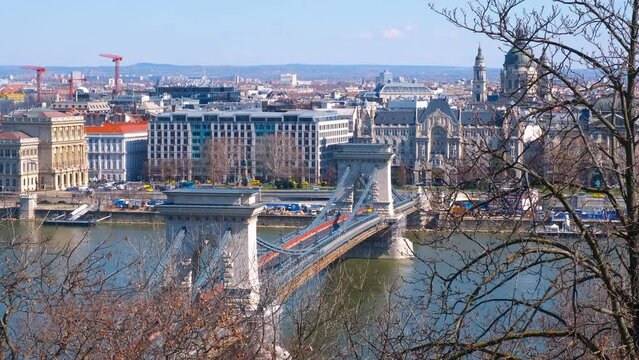 Secheni bridge through river in budapest. A nice old Secheni bridge over Danube river against famous Budapest buildings in the sun.