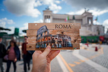 Hand holding Colosseum postcard in Rome, Italy. ROMA and COLOSSEO on the postcard, blurred...