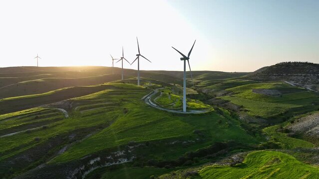 Aerial view of windmills on a green field. Green energy ecological production of electricity from the wind. High quality 4k footage