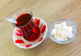 Turkish hot black tea served in traditional glass cup on saucer with sugar cubes