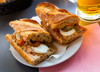 Traditional French pan bagnat - delicious sandwich with tuna, hard boiled eggs, anchovies and stewed bell peppers..
