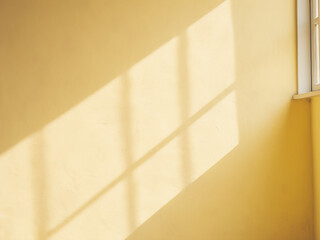 Pale yellow wall casts window shadows in an abstract background