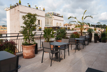 Explore a luxurious rooftop terrace in Rome with modern outdoor furniture, lush greenery, and...