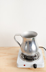 Metal container placed on electric resistance to heat soy vegetable wax for sustainable, organic,...