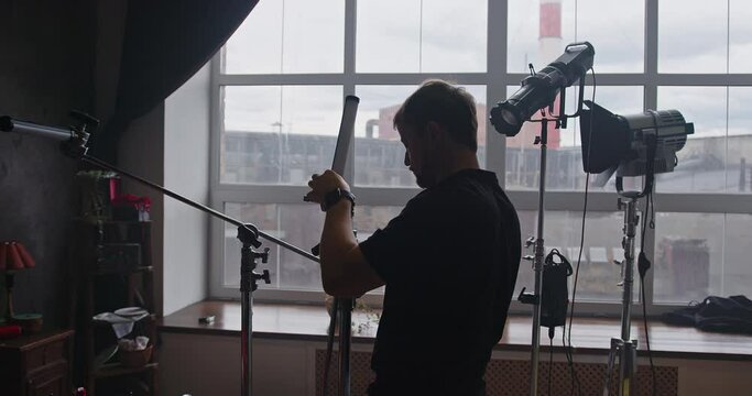 A lighting designer adjusts a lighting fixture on a film set.