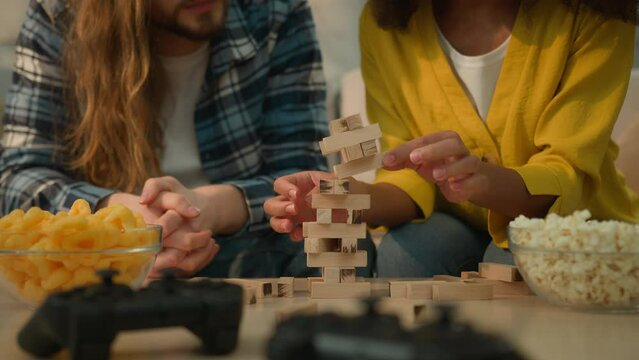Multiracial couple diversity Caucasian man African American woman boyfriend husband and wife girlfriend at home couch playing game wooden blocks tower fun happy play Jenga girl fall lost laughing joy