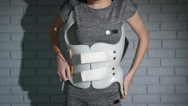 Girl wearing scoliosis brace. A view of plastic orthopedic corset on the teen back during treatment period.