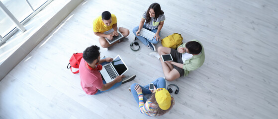 Students with modern devices studying online indoors