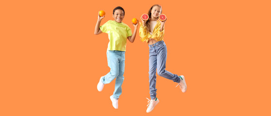 Little children with fresh citruses jumping on orange background