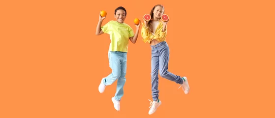 Fotobehang Little children with fresh citruses jumping on orange background © Pixel-Shot