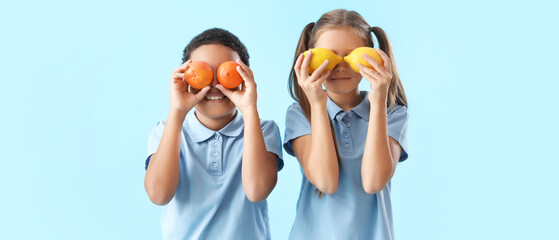 Happy little children with fresh citruses on blue background