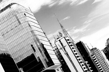 Prédios com fachada de vidro, antena de comunicação e céu nublado. Paisagem urbana futurista de arquitetura moderna na cidade de São Paulo, Brasil.  - obrazy, fototapety, plakaty
