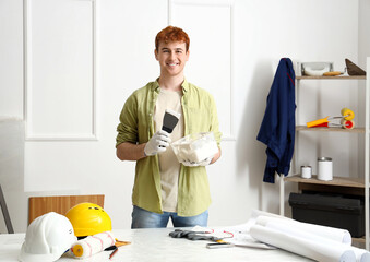 Young man with putty knife and plaster working at home