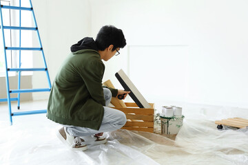 Young Asian man with putty knife in room