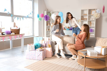 Young pregnant woman with her friends drinking at baby shower party