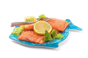 Pieces of Salmon filet on a blue fish shaped plate with lemon slice and garnish ready to be cooked isolated on white

