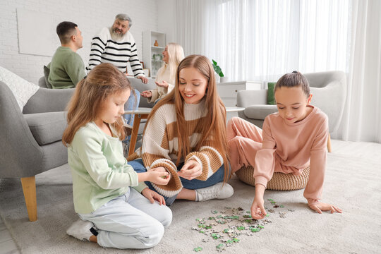 Happy mother with her little daughters doing puzzle at home